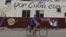 Un hombre cruza en bicicleta frente a un muro con mensajes alusivos a las elecciones generales en Cuba.