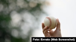 Primer plano de una mano sosteniendo una pelota de béisbol en un campo deportivo / Imagen de archivo