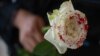 Una mujer sostiene una rosa "ensangrentada" en señal de luto por los feminicidios. (Pedro Pardo / AFP)